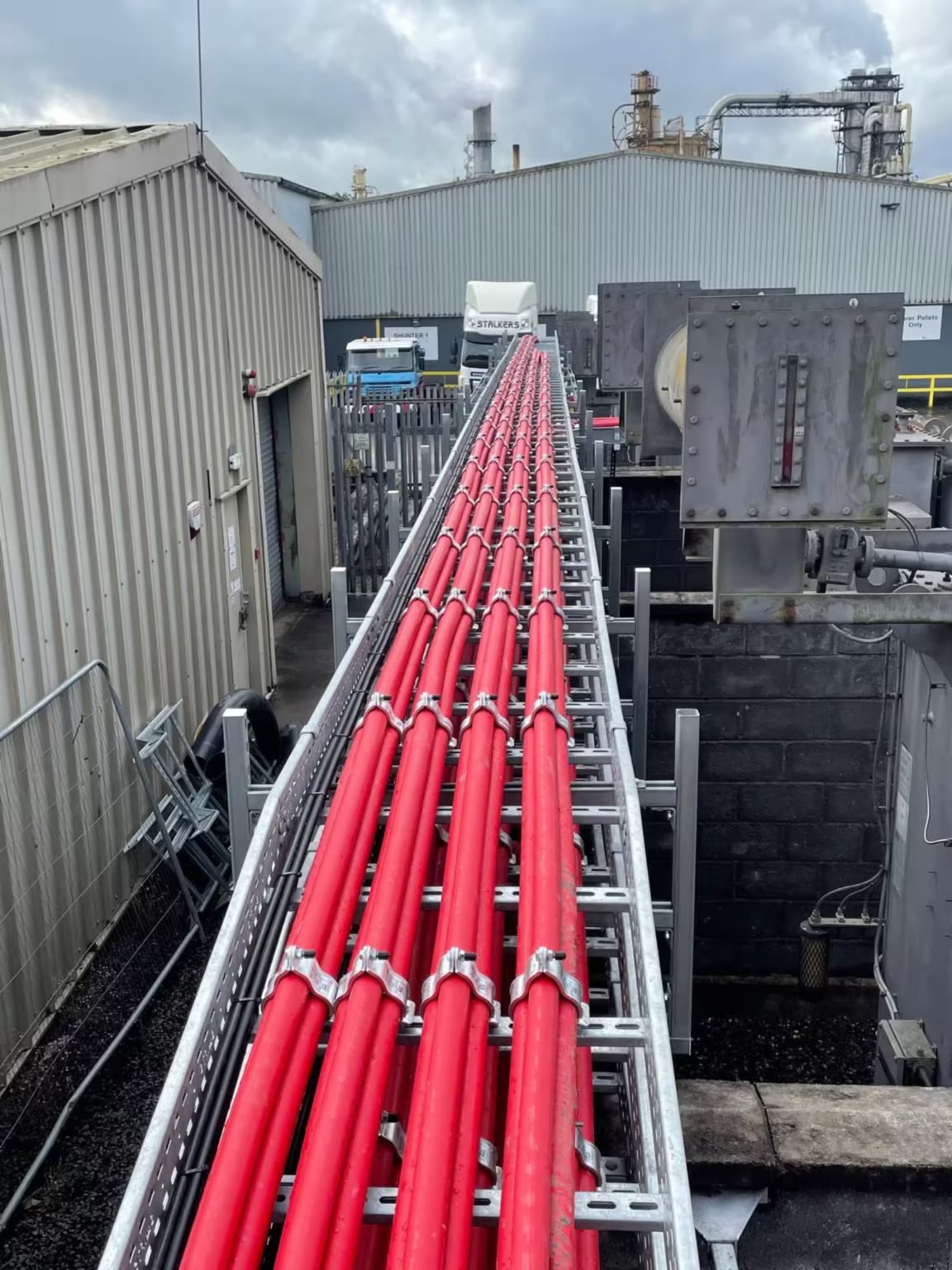 Red HV cables cleated along a steel ladder rack through an industrial yard