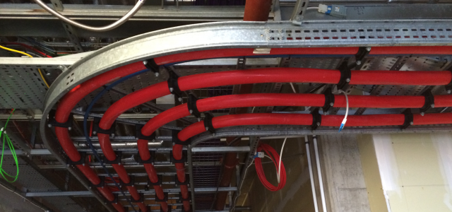 Red power cables cleated around a bend on a steel tray